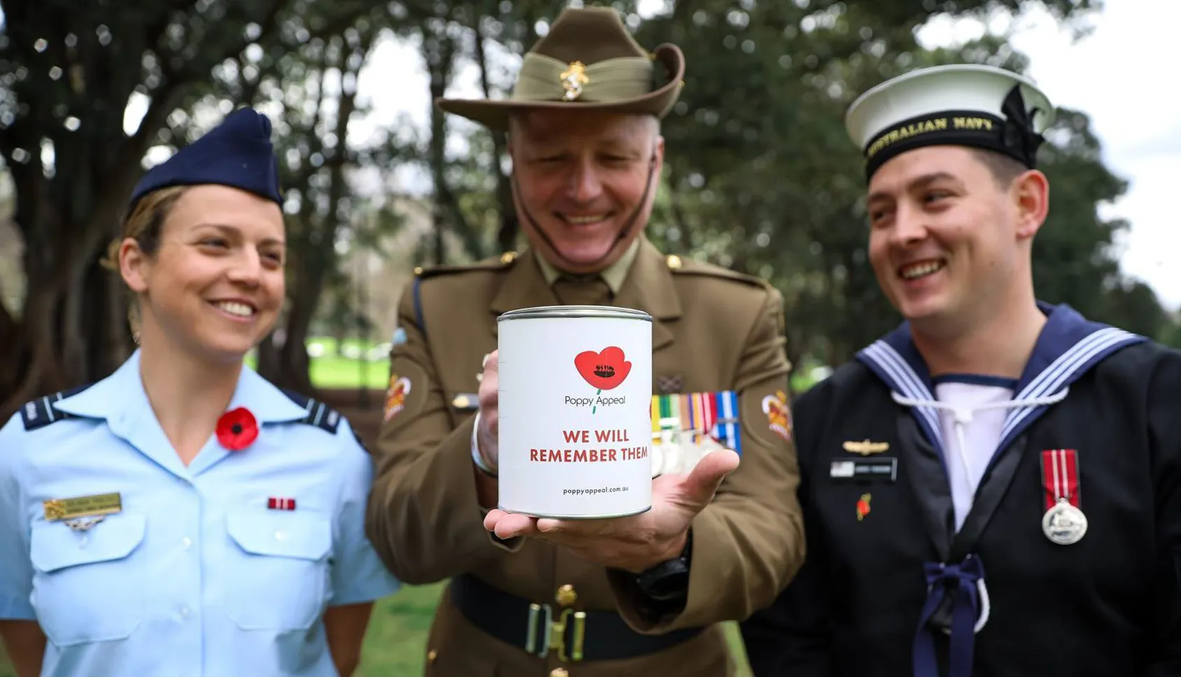 Veterans holding up a Poppy Appeal donation tin